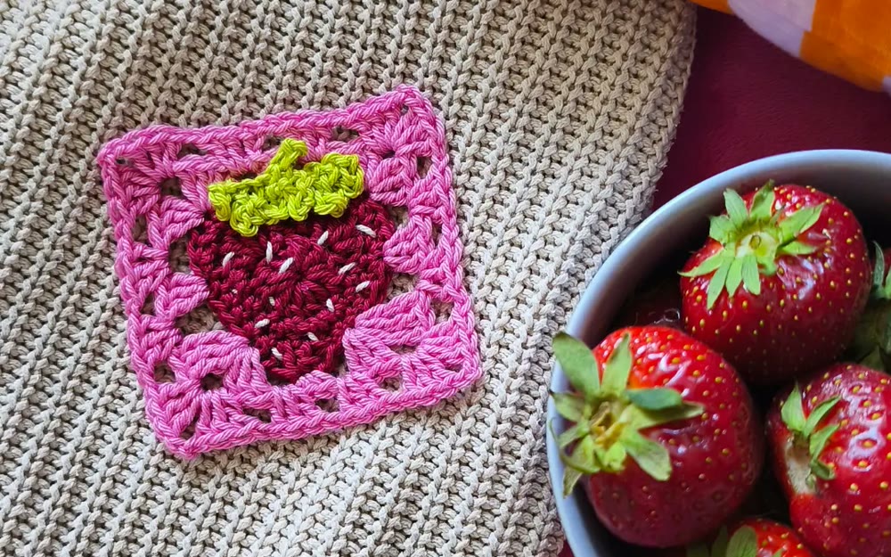 Granny square z truskawką obok miski truskawek
