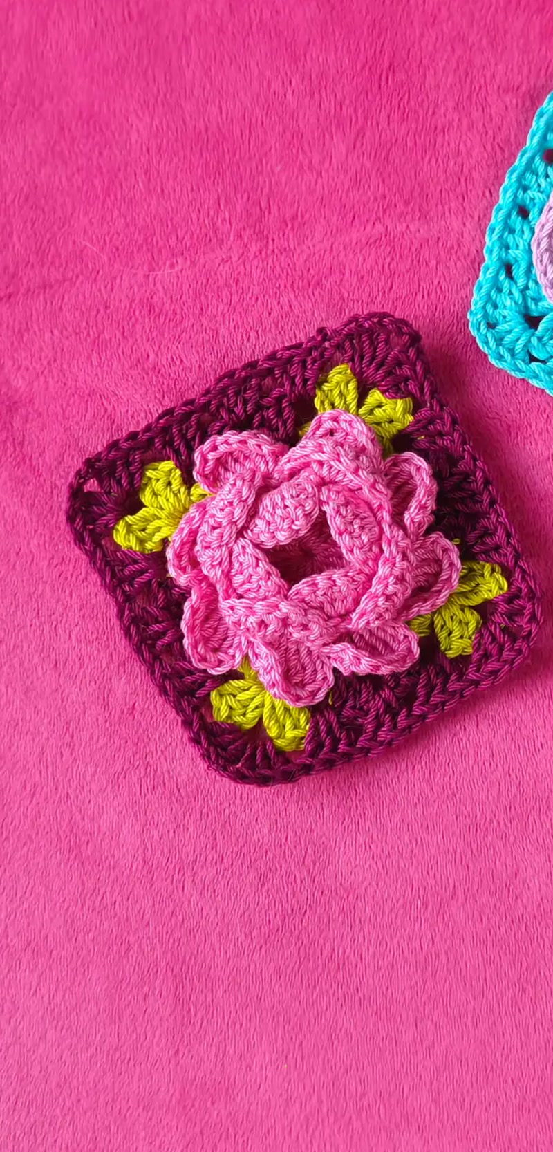 Dwa kolorowe granny squares z kwiatami na różowym tle
